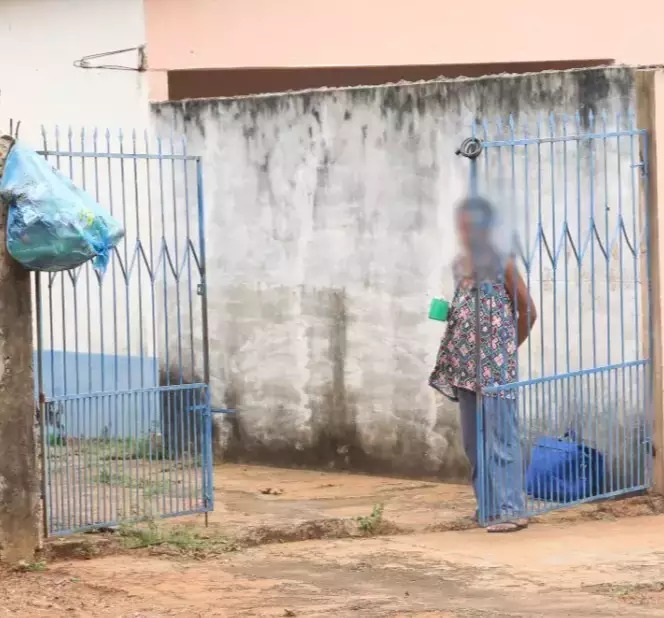 Idosa em frente de casa, já com portão aberto, após denúncia de abandono